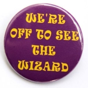 May include: Purple button with yellow text that reads "We're Off To See The Wizard".