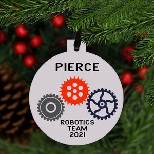 May include: White round Christmas ornament with the text "PIERCE ROBOTICS TEAM 2021" and three gears, one red, one gray, and one blue.