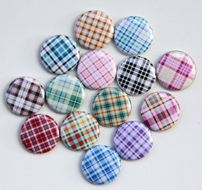 Puede incluir: Doce botones redondos con diferentes patrones de cuadros. Los botones son de varios colores, incluyendo azul, verde, rojo, rosa y marr&oacute;n.