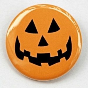 May include: Orange round button with a black jack-o'-lantern face. The face has two triangle eyes, a triangle nose, and a wide, toothy grin.