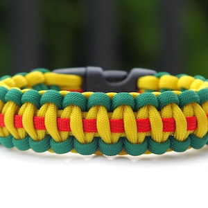 May include: A green, yellow, and red paracord bracelet with a black plastic clasp.