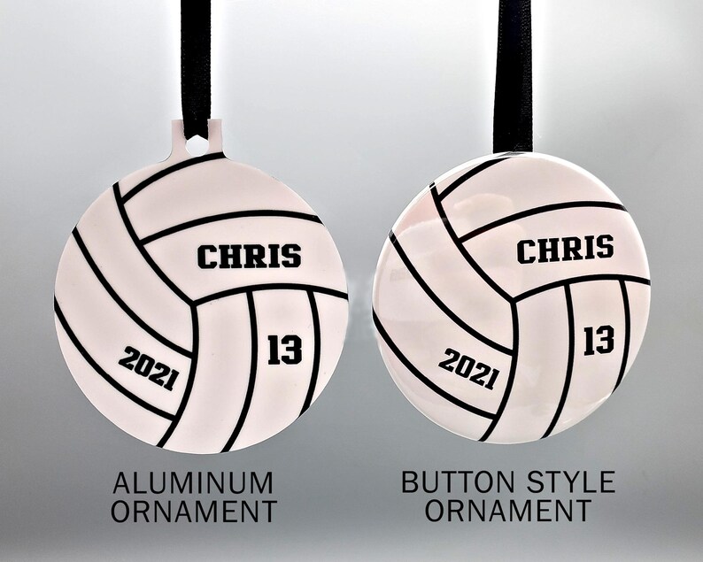 May include: Two white volleyball ornaments with black stitching and black text. The ornament on the left is labeled "Aluminum Ornament" and the ornament on the right is labeled "Button Style Ornament". Both ornaments have the text "CHRIS 13 2021" on them.