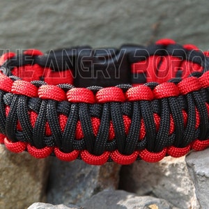 Puede incluir: Pulsera de paracord negra y roja con una hebilla negra. La pulsera est&aacute; hecha con un patr&oacute;n de tejido cobra.