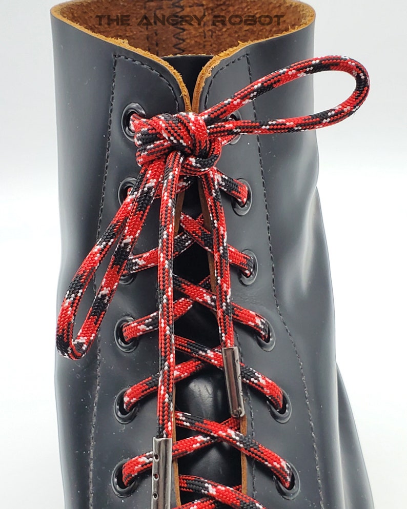May include: Black leather boots with red, white, and black shoelaces. The laces are tied in a criss-cross pattern and secured with silver metal lace locks.