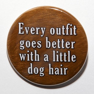 May include: A brown round button with white text that reads "Every outfit goes better with a little dog hair."