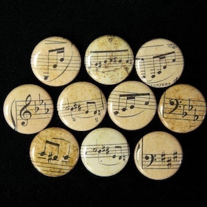 May include: Ten round, cream-coloured buttons with black musical notes printed on them. The buttons have a distressed, vintage look.