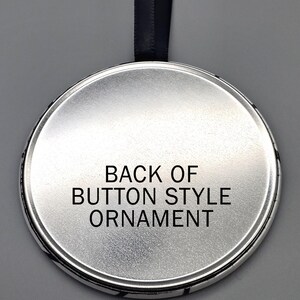 May include: The back of a silver round button style ornament with a black ribbon attached. The text "BACK OF BUTTON STYLE ORNAMENT" is printed on the back of the ornament.