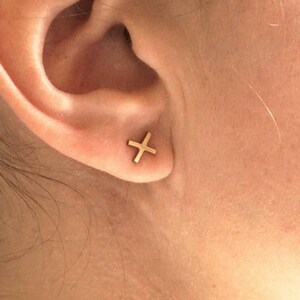 May include: A close-up of a person's ear with a small gold cross earring.
