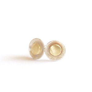 May include: A pair of silver stud earrings with a small, round, gold disc in the center.