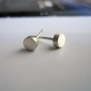 May include: A pair of silver stud earrings with round, flat tops.