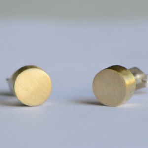 May include: A pair of gold-toned round stud earrings with a brushed finish.