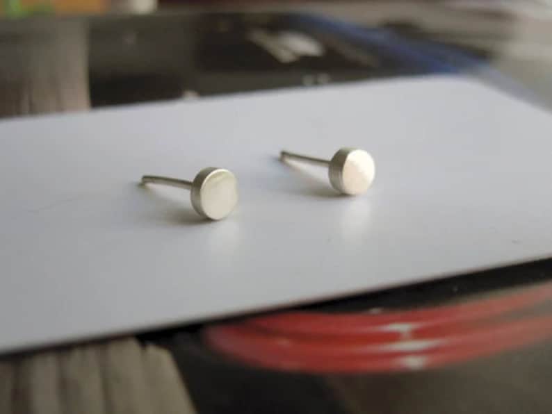 May include: A pair of silver stud earrings with round, flat tops.