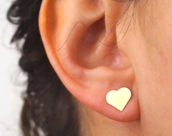 Puede incluir: Primer plano de una oreja con un pequeño pendiente de corazón de oro.