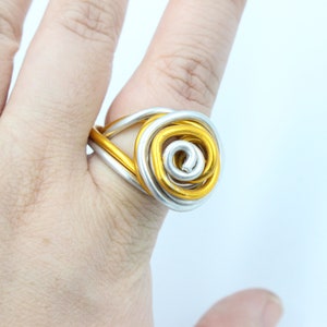 May include: A gold and silver wire ring with a rose design.