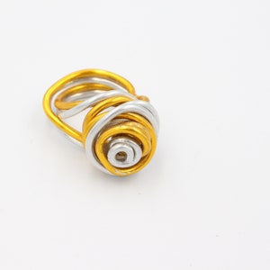 May include: A gold and silver wire ring with a spiral design.