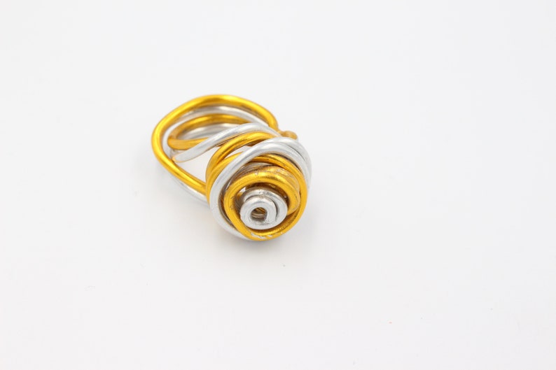 May include: A gold and silver wire ring with a spiral design.