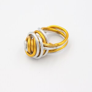 May include: A gold and silver wire ring with a twisted knot design.