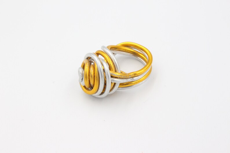 May include: A gold and silver wire ring with a twisted knot design.