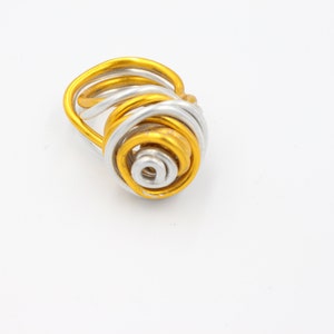 May include: A gold and silver wire ring with a spiral design.