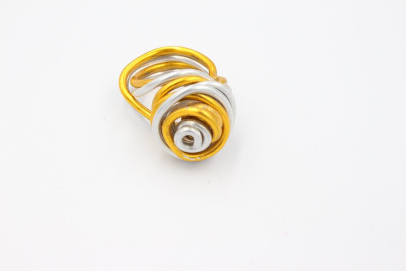 May include: A gold and silver wire ring with a spiral design.