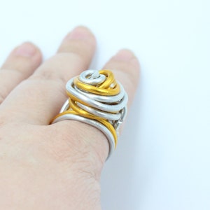 May include: A gold and silver wire ring with a unique, twisted design. The ring is large and appears to be handmade.