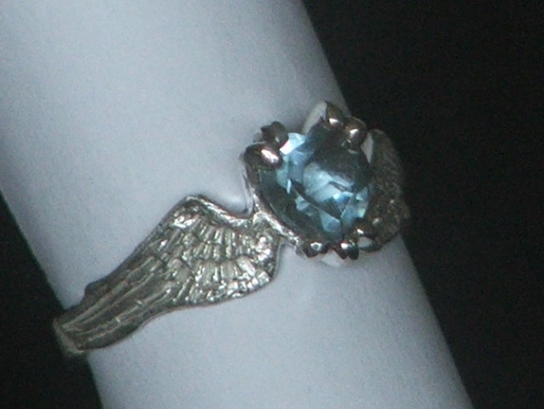May include: A silver ring with a light blue gemstone set in a wing design.