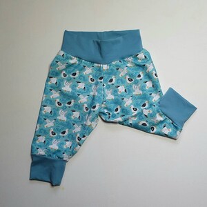 May include: Blue baby trousers with a white seagull pattern. The trousers have a blue elastic waistband and cuffed legs.