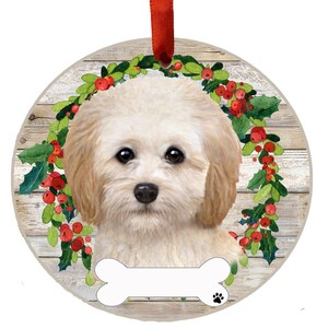 May include: A white and cream colored dog with a bone shaped ornament. The dog is surrounded by a green wreath with red berries. The background is a woodgrain pattern.