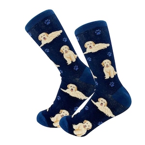Op de afbeelding: Een paar blauwe sokken met een patroon van witte golden retriever honden en voetafdrukken.