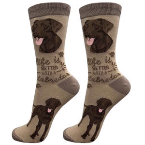 Peut inclure: Une paire de chaussettes brunes et beiges avec un chien Labrador Retriever chocolat sur chaque chaussette. Les chaussettes portent le texte "La vie est meilleure avec un Labrador".