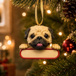 May include: A hanging Christmas tree ornament featuring a sculpted pug dog head with a black muzzle and ears, light tan fur, and a pink tongue. The pug rests its front paws on a blank, rectangular, cream-colored sign with a red border.