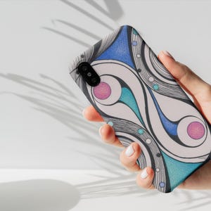 Può includere: Una custodia per smartphone con un design astratto. La custodia presenta uno sfondo bianco con linee e forme curve nere, blu, turchesi e rosa. La custodia è tenuta in mano su uno sfondo bianco.