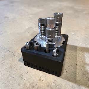 Può includere: Un organizer per utensili rettangolare nero con più scomparti e utensili cilindrici in metallo. L'organizer presenta il testo "CMBprecision" sul davanti. Gli utensili sono argentati e neri.