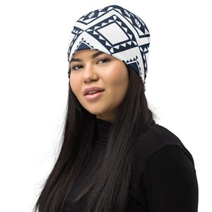 May include: A white beanie with a navy blue geometric pattern. The beanie is made of a soft, stretchy fabric and is perfect for keeping your head warm in the winter.