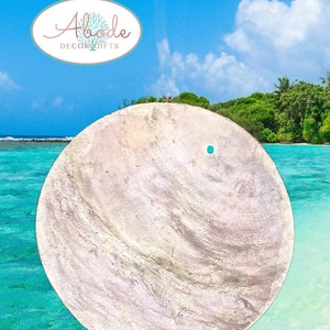 May include: A large, round, textured decorative item with a light gray and white color scheme. A small turquoise accent dot is visible. The image includes the text "Abode Decor Gifts" in a logo at the top.