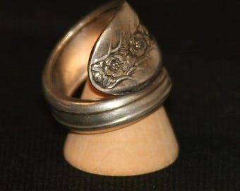 Könnte beinhalten: Ein silberner Löffelring mit einem floralen Design. Der Ring ist aus einem gebogenen Löffel gefertigt und hat eine glatte, polierte Oberfläche.