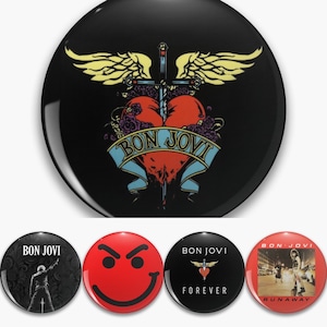May include: A selection of Bon Jovi band badges. The main badge displays a heart pierced by a sword, wings, and a banner with the band's name. Other badges include a smiley face, album art, and the band's logo.