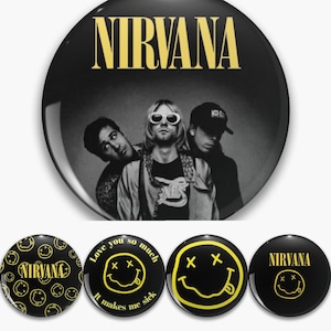 May include: A selection of black and yellow Nirvana band badges. The largest badge displays a black and white band photo with the band's name in gold. Other badges feature the smiley face logo and text, including "Love you so much, it makes me sick."