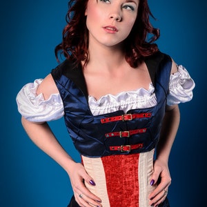 May include: A woman wearing a blue and red corset with a white ruffle collar and white sleeves. The corset has a quilted design and is fastened with silver buckles. The corset is worn over a white shirt and blue skirt.