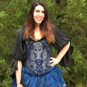 May include: A woman wearing a blue and silver corset with a black top and a blue ruffled skirt.