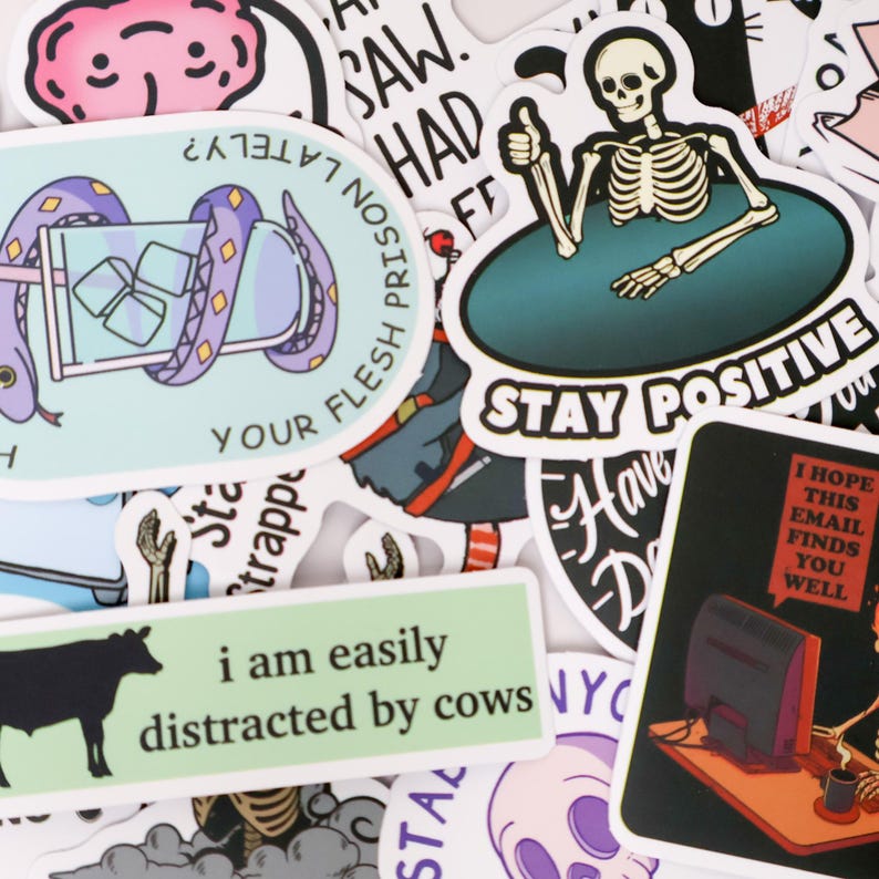 Puede incluir: Una colecci&oacute;n de pegatinas coloridas con varios dise&ntilde;os y texto. Una pegatina presenta un esqueleto haciendo una se&ntilde;al de pulgar hacia arriba con las palabras "Stay Positive". Otra dice "I am easily distracted by cows". Otras pegatinas tienen frases e ilustraciones.