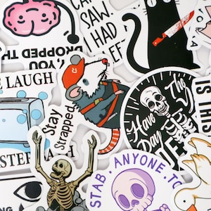 Puede incluir: Una colecci&oacute;n de varias pegatinas con ilustraciones de dibujos animados y texto. Las pegatinas presentan una rata con un atuendo de construcci&oacute;n, un gato negro con un cuchillo, un esqueleto y un cerebro. El texto incluye "SAW. I HAD EF", "Stay Strapped" y "Have a Day".