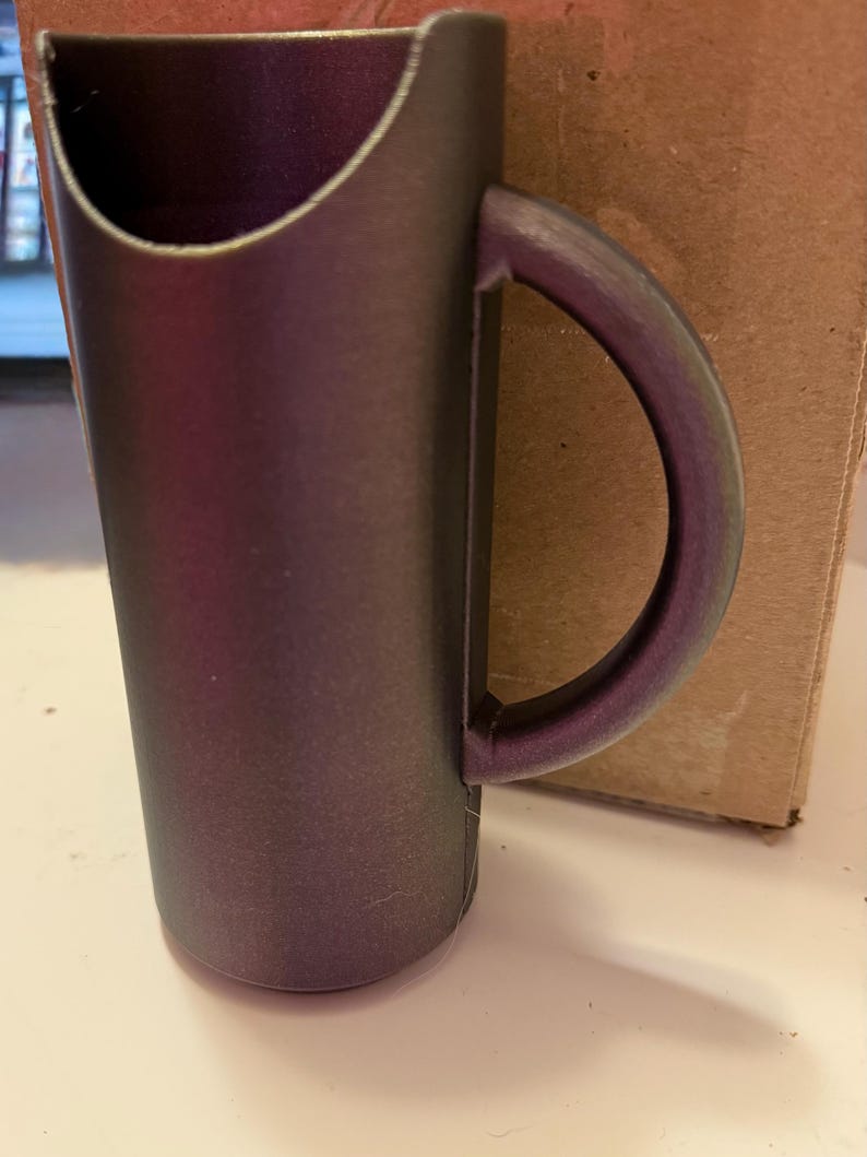 May include: A dark purple plastic cup with a handle. The cup has a wide opening and a narrow base.