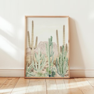 May include: A framed print of a watercolor illustration of a desert landscape with multiple cacti in shades of green against a white background.