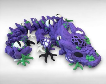 May include: A purple dragon sculpture with white eyes, green accents, and black details. The dragon has a textured body and is posed in a curved shape. The sculpture is made of a solid material.