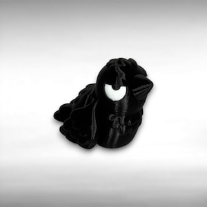 May include: A 3D-printed black bird figurine with a large, white, crescent-shaped eye. The bird has a rounded body, small wings, and a pointed beak. The figurine is set against a white background.