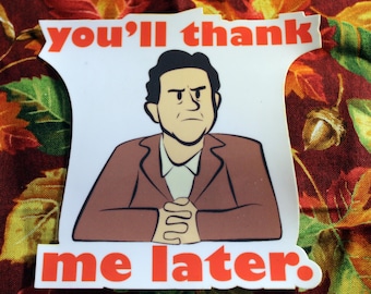 Può includere: Un adesivo bianco con la scritta "you'll thank me later" in arancione. L'adesivo presenta un'illustrazione a cartoni animati di un uomo in abito marrone con le braccia incrociate e un'espressione severa. Lo sfondo è un tessuto a tema autunnale.