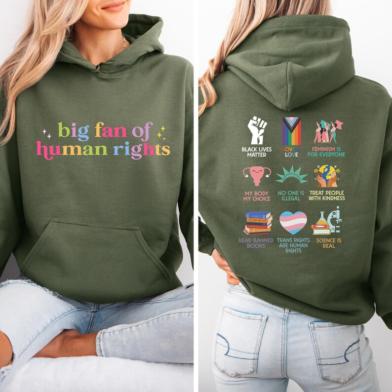 May include: An olive green hoodie with the text "big fan of human rights" in colourful letters on the front. The back of the hoodie features various social justice symbols and phrases, including "Black Lives Matter" and "Feminism is for Everyone."