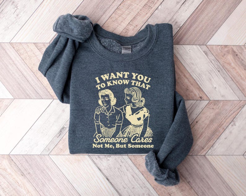 May include: A dark gray sweatshirt with the text "I want you to know that someone cares not me, but someone" and a retro illustration of two women.