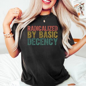 May include: A black t-shirt with a vintage-style graphic that reads "Radicalized by Basic Decency".